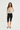 Woman wearing a polka dot top and black capri pants on a white background