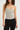 Woman wearing a polka dot top and black pants on a white background