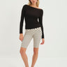 Woman wearing a black long-sleeve top and nude capri pants with black polka dot pattern on a white background