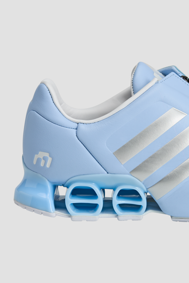 Light blue adidas athletic shoes with silver stripe white soles and a zipper tongue on a light gray background